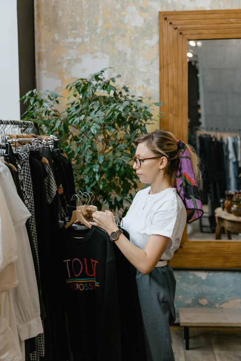Fashion-conscious woman browsing a boutique clothing rack with elegant apparel indoors.