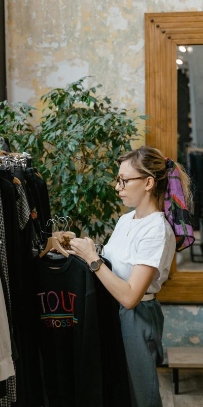 Fashion-conscious woman browsing a boutique clothing rack with elegant apparel indoors.
